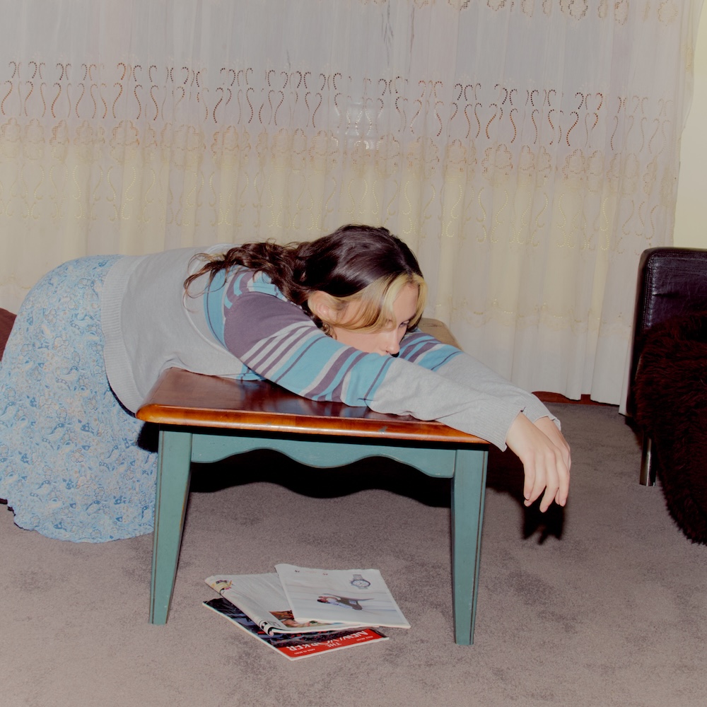 Single cover artwork for Grace Robinson's song driving, featuring a woman leaning face-down over a small wooden table.